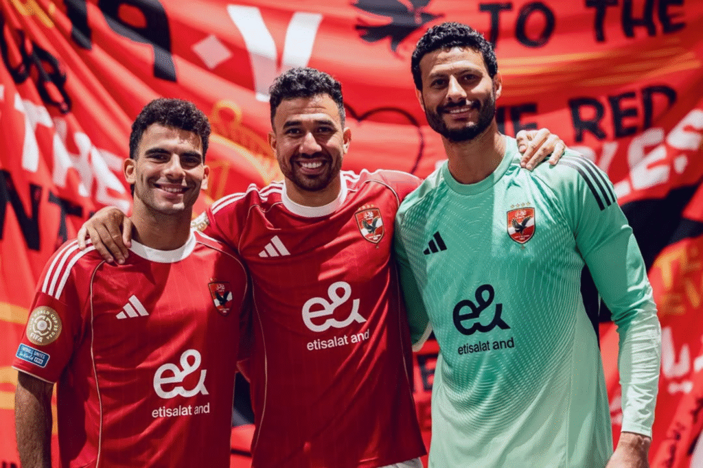 Tres jugadores de Al Ahly sonríen frente a una bandera del club durante la sesión oficial de fotos previa al Mundial de Clubes.