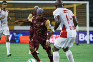 Jugador de Deportes Tolima avanza con el balón frente a un defensor de América de Cali durante un partido de la liga colombiana.