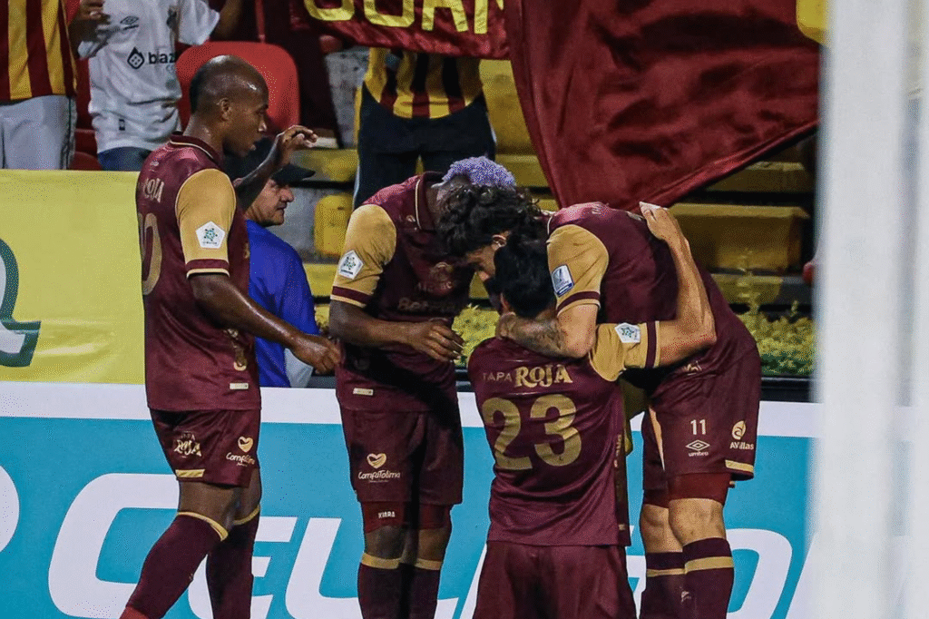 Jugadores de Deportes Tolima celebran un gol con abrazos frente a la hinchada, durante el partido ante América de Cali.
