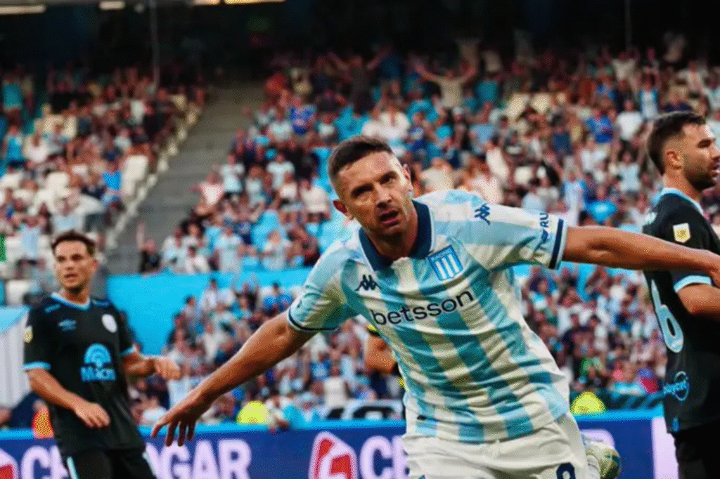 Maravilla Martínez celebrando un gol en un partido de Racing, con los logos de Betsson, Rus y Cetrogar claramente visibles en su camiseta, representando el crecimiento de las sponsorizaciones.
